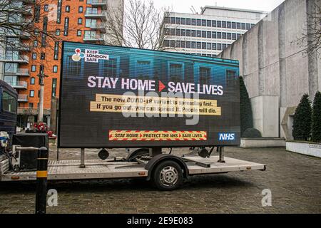 PUTNEY LONDON, REGNO UNITO. 4 Feb 2021. La gente cammina oltre un grande segno digtial di informazioni da NHS Inghilterra in Putney High Street come parte della campagna del governo di NHS per mantenere Londra sicuro dopo che una nuova variante del Covid-19 sudafricano è stata scoperta senza collegamenti al Sudafrica in otto codici postali in Inghilterra e nel sud East Credit: amer Ghazzal/Alamy Live News Foto Stock