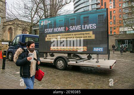 PUTNEY LONDON, REGNO UNITO. 4 Feb 2021. La gente cammina oltre un grande segno digtial di informazioni da NHS Inghilterra in Putney High Street come parte della campagna del governo di NHS per mantenere Londra sicuro dopo che una nuova variante del Covid-19 sudafricano è stata scoperta senza collegamenti al Sudafrica in otto codici postali in Inghilterra e nel sud East Credit: amer Ghazzal/Alamy Live News Foto Stock