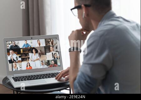 Vista dal retro sopra la spalla del notebook con diversi dipendenti, colleghi sullo schermo, videochiamata, riunione online. App per videoconferenza con Foto Stock