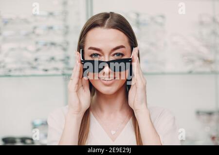 Giovane Donna con occhiali neri punzonati per l'allenamento visivo. Trainer per occhiali perforati. Foto Stock