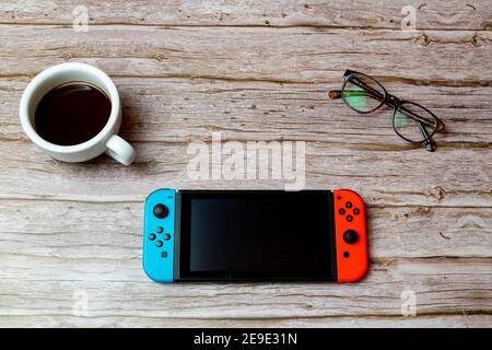 Una console di gioco Nintendo Switch disposta su una scrivania o. tavolo accanto a un caffè e bicchieri Foto Stock