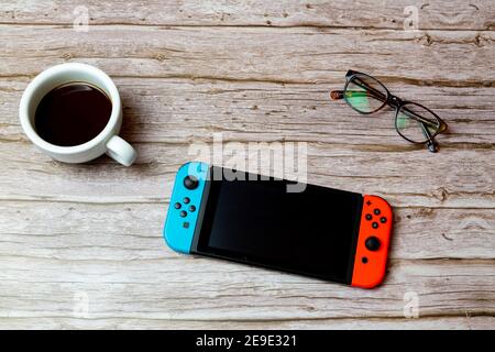 Una console di gioco Nintendo Switch disposta su una scrivania o. tavolo accanto a un caffè e bicchieri Foto Stock