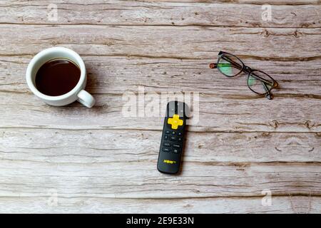 02-04-2021 Portsmouth, Hampshire, UK UN telecomando TV Yellow Now posto su un tavolo o scrivania accanto a bicchieri e un caffè Foto Stock