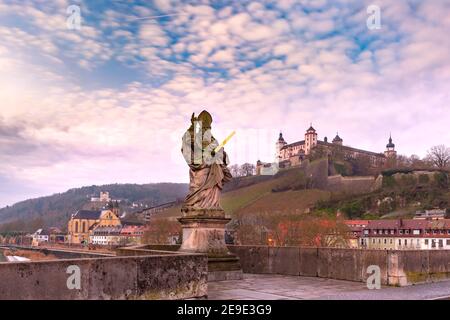 Statua di San Kilian sul vecchio ponte principale, Alte Mainbrucke, con la Fortezza Marienberg sullo sfondo, Wurzburg, Baviera, Germania Foto Stock