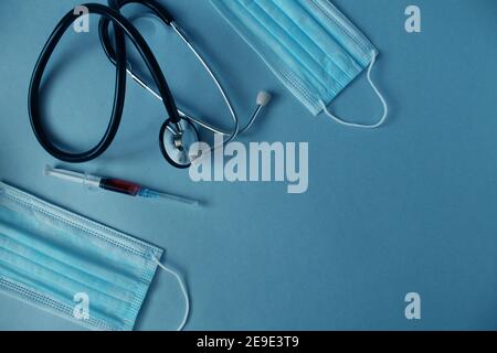 Flatlay medicina sfondo siringa stetoscopio giacciono su uno sfondo blu con un posto per il testo con una vista copyspace dall'alto. Foto Stock