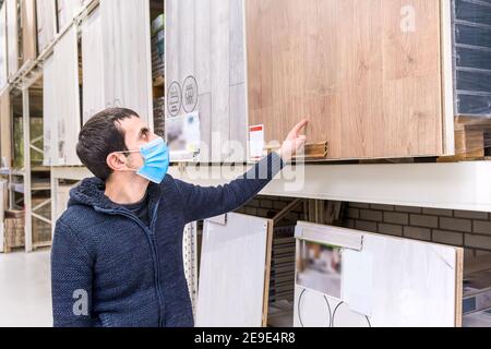Un uomo in un negozio di ferramenta sceglie un laminato. Messa a fuoco selettiva. Persone. Foto Stock