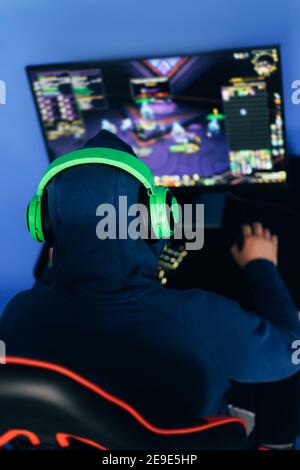 Il tipo del giocatore gioca ai giochi del calcolatore. Un hobby moderno, giocare giochi per computer. Foto verticale, vista dall'alto. Foto Stock