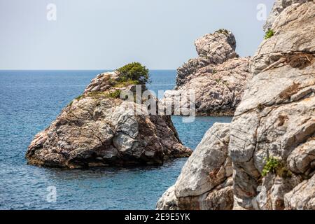 Big Rock nelle acque blu di Stafilos Beach, Skopelos, Skopelos Island, Grecia in una calda giornata estiva. Foto Stock