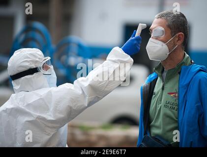 Malaga, Spagna. 04Feb 2021. Un operatore sanitario che indossa una tuta per dispositivi di protezione individuale (PPE) controlla la temperatura di un uomo fuori da una cancelleria di prova del coronavirus durante un test di covid-19 massiccio a Plaza Limeno piazza nel centro della città. A causa dell'elevato tasso di infezioni da coronavirus nella capitale di Malaga, circa 1.600 volontari sono stati selezionati dalle autorità sanitarie per partecipare a un test casuale per la covid-19 dell'antigene. Credit: SOPA Images Limited/Alamy Live News Foto Stock