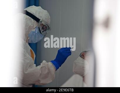 Malaga, Spagna. 04Feb 2021. Un operatore sanitario che indossa una tuta protettiva personale (PPE) raccoglie campioni di swap da un uomo all'interno di una cancelleria di prova del coronavirus durante un test di covid-19 massiccio a Plaza Limeno piazza nel centro della città. A causa dell'elevato tasso di infezioni da coronavirus nella capitale di Malaga, circa 1.600 volontari sono stati selezionati dalle autorità sanitarie per partecipare a un test casuale per la covid-19 dell'antigene. Credit: SOPA Images Limited/Alamy Live News Foto Stock