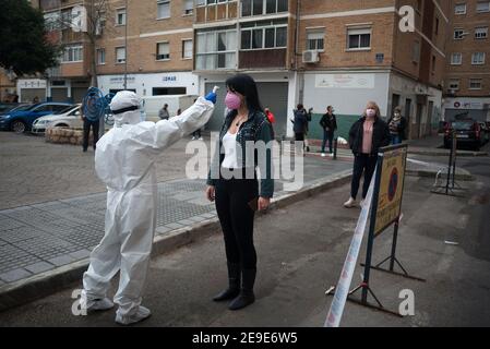 Malaga, Spagna. 04Feb 2021. Un operatore sanitario che indossa una tuta per dispositivi di protezione individuale (PPE) controlla la temperatura di una donna all'esterno di una stazione di test del coronavirus durante un test di covid-19 massiccio a Plaza Limeno nel centro della città. A causa dell'elevato tasso di infezioni da coronavirus nella capitale di Malaga, circa 1.600 volontari sono stati selezionati dalle autorità sanitarie per partecipare a un test casuale per la covid-19 dell'antigene. Credit: SOPA Images Limited/Alamy Live News Foto Stock