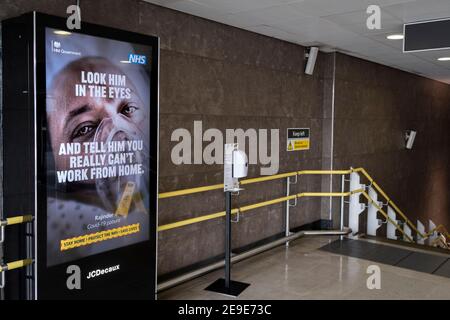 Un annuncio del governo NHS (National Heath Service) che mostra il volto di un paziente di Covid, si trova in cima a una scalinata in una stazione ferroviaria deserta di Blackfriars durante il terzo blocco della pandemia di Coronavirus, nella 'City of London', il quartiere finanziario della capitale, alias Square Mile, Il 2 febbraio 2021, a Londra, Inghilterra. Foto Stock