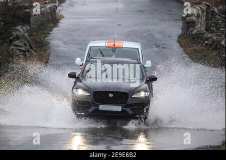 Langshaw, vicino a Galashiels Scottish Borders, Regno Unito. 4 Feb 2021. Scozia, Regno Unito Wet Rain Weather. Quando la pioggia battente cade dopo recenti cadute di neve, il terreno saturo provoca un accumulo di acqua di superficie sulle strade. Le immagini mostrano auto e furgoni che attraversano una grande e profonda pozza che si è formata su una strada a Langshaw, ai confini scozzesi. Credit: phil wilkinson/Alamy Live News Foto Stock