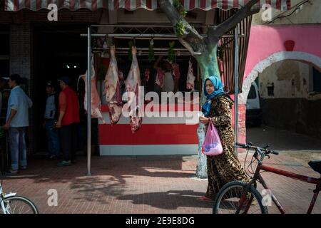 El Jadida, Marocco - 16 aprile 2016: Una donna che passa di fronte ad un macellaio, nella città di El Jadida. Foto Stock