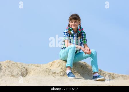 Una ragazza di dieci anni si siede su una collina e. sorrisi Foto Stock