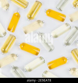 Collezione bottiglie trasparenti con diversi colori chiari liquido, prodotto cosmetico, profumo o bevanda e tappo argento su sfondo bianco come decorativo Foto Stock