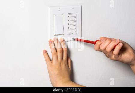 Il tecnico stringe l'ultima vite sul timer della ventola e. interruttore luci Foto Stock