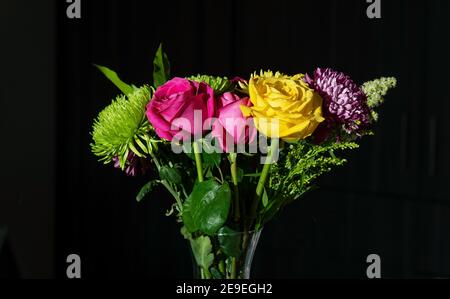 Bouquet di fiori di San Valentino con rose e crisantemi di colore giallo ecuadoriano e fucsia con sfondo nero. Foto Stock