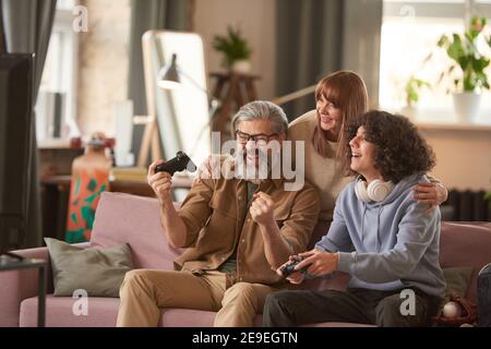 Papà è felice della sua vittoria nel gioco lui vincendo suo figlio mentre giocano i videogiochi insieme a. casa Foto Stock