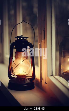 Una vecchia lampada cherosene si trova su un davanzale bianco la sera Foto Stock