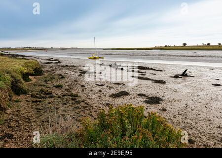 Barca sull'estuario della Swale a bassa marea a Oare vicino a Faversham in Kent, che domina l'isola di Sheppey Foto Stock