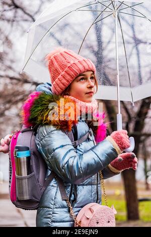 ragazza in giacca con ombrello trasparente sotto la pioggia al freddo.  Adolescente sotto un ombrello Foto stock - Alamy