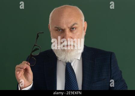 Professore o insegnante serio. Insegnante di uomo anziano su una lavagna vuota durante la lezione, lezione di insegnamento all'università. Pensi il senior. Foto Stock