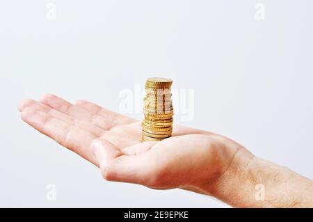Uomini caucasici mano tenendo una pila di soldi (monete d'oro), su sfondo bianco, isolato, vista laterale Foto Stock