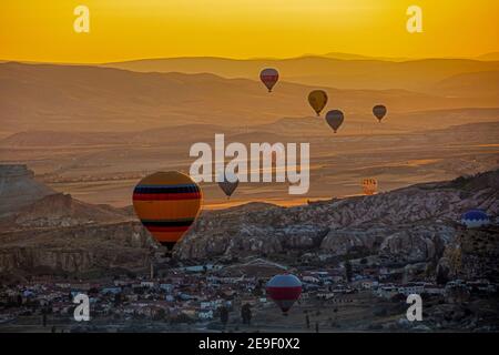 Mongolfiere che sorvolano la città di Göreme in Cappadocia all'alba, nella provincia di Nevşehir, nell'Anatolia centrale, Turchia Foto Stock