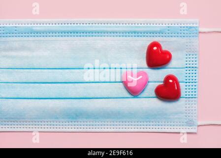 primo piano della maschera chirurgica protettiva con un cuore su rosa Background.concetto epidemico di Coronavirus Foto Stock