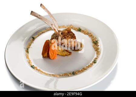 costolette di agnello in crosta di nocciola in piatto bianco isolato su bianco Foto Stock