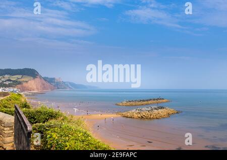 La spiaggia di sabbia e le isole rocciose che guardano ad est a Sidmouth, una cittadina costiera del Devon sulla Jurassic Coast, patrimonio mondiale dell'umanità, con bassa marea in una giornata di sole Foto Stock