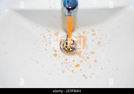 Ruggine che scorre dal rubinetto in bagno. Il concetto del problema è acqua sporca Foto Stock