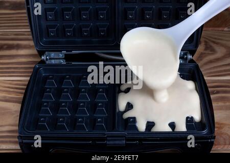 Waffle ferro da stiro in cucina. Preparare i waffle fatti in casa e versare un impasto. Cialde viennesi belghe Foto Stock