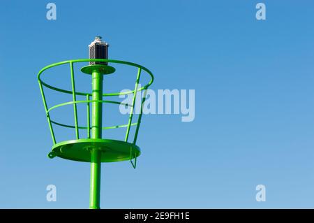 Dettaglio del segnalatore luminoso verde, segnale luminoso di navigazione per l'ingresso in un porto, ad energia solare, concetto di sicurezza e navigazione Foto Stock