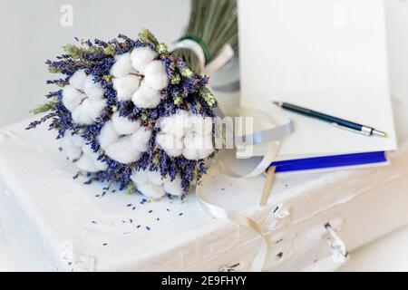 Fiori di lavanda e piante di cotone su valigia vintage, carta aperta per il testo. Naturale romantico eco regalo Foto Stock