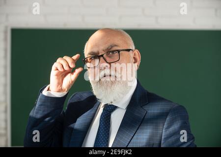 Insegnante di uomo anziano su una lavagna vuota durante la lezione, lezione di insegnamento all'università. Pensi il senior. Giornata degli insegnanti. Foto Stock