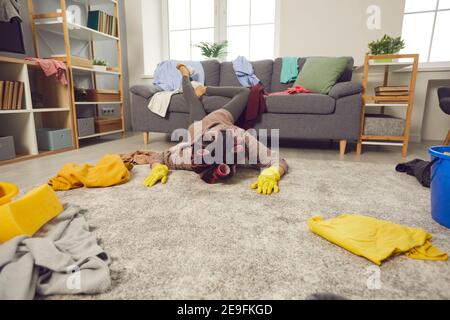 Una casalinga molto stanca è caduta a faccia in giù sul pavimento durante la pulizia il suo appartamento disordinato Foto Stock