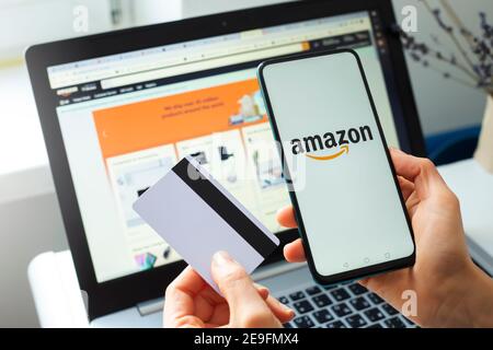 Kiev, Ucraina - 02 febbraio 2021: Acquisto di beni nel negozio online Amazon utilizzando uno smartphone, un computer portatile e una carta di credito. Foto Stock