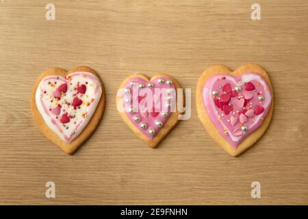 Una fotografia di tre biscotti a forma di cuore dall'alto, sfondo del piano di lavoro della cucina. Foto Stock