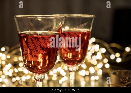 Primo piano di un paio di bicchieri con vino. Il bokeh si illumina sullo sfondo. Composizione romantica. Foto Stock