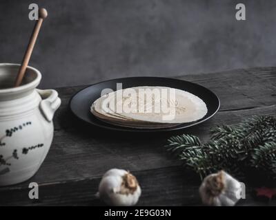 Wafer della vigilia di Natale con pentola di miele e bulbi di aglio su tavolo di legno. Buio e moody. Spazio di copia. Foto Stock