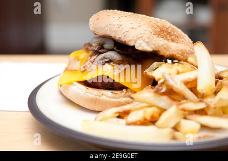cheeseburger e funghi saltati e cipolle con patatine fritte Foto Stock