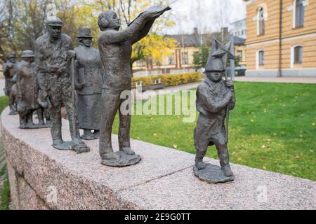 OULU, FINLANDIA - 12 ottobre 2020: Il passaggio del tempo della scultura in bronzo di Sanna Koivisto raffigura persone di secoli diversi. Piccolo ragazzo finale che cammina Foto Stock