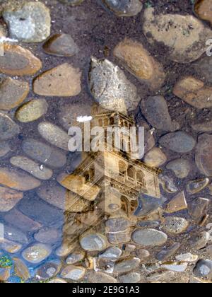 La campana della torre modenese di nome Ghirlandina si riflette in una pozza a Modena, Italia Foto Stock