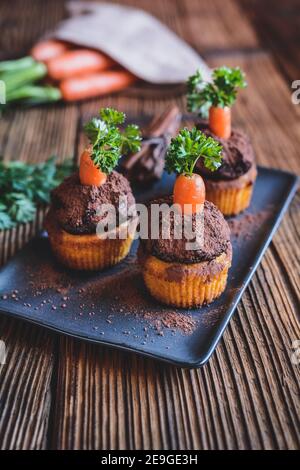 Muffin di carote dolci conditi con crema di cocco e cioccolato, cosparsi di cacao in polvere Foto Stock