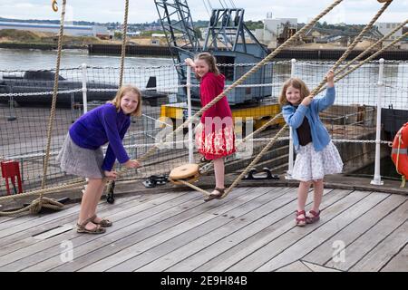 Ragazze di dieci, 8 e 6 anni turisti visitatori bambini / bambini esplorare la manipolazione e il ponte di HMS Gannet, presso Historic Dockyard / Dockyards Chatham a Kent, Regno Unito. (121) Foto Stock