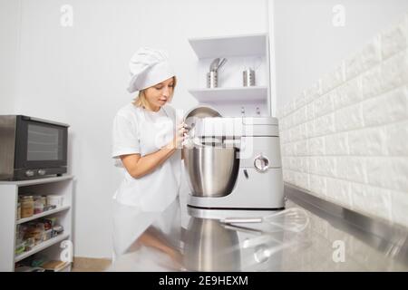 Chef pasticceria femminile che utilizza un miscelatore elettrico durante la  cottura nella cucina da forno Foto stock - Alamy