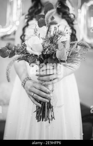 Scala di grigi ripresa di una sposa ho un creativo diseveled matrimonio bouquet Foto Stock