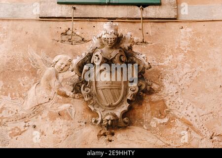 Un bassorilievo sulla facciata di un edificio nel centro storico di Cattaro in Montenegro. Scudo e armatura di Cavaliere, colomba e angeli. Foto Stock